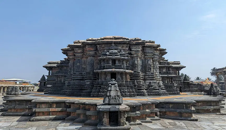 Historic stone temple with intricately carved pillars and detailed sculptures, set against a clear blue sky.