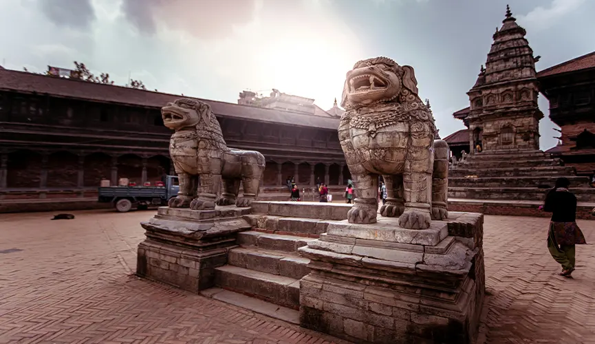 Ancient stone lions guarding the steps of a historic temple courtyard, with traditional architecture in the background.