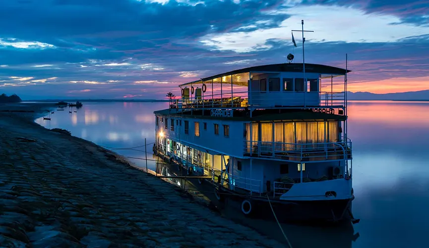 A boat docked on a river at sunset.