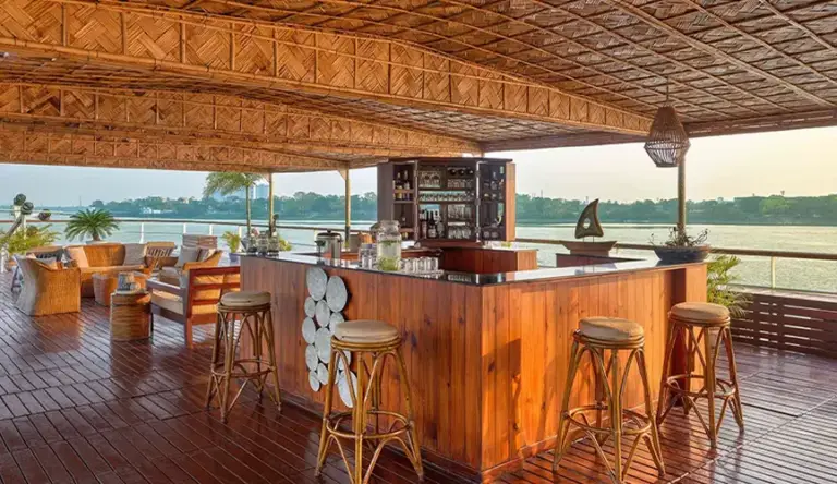 Wooden bar and seating area on a riverside deck.