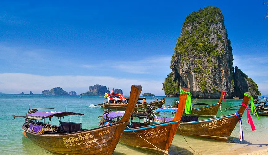 Longtail boats anchored near a rocky island.