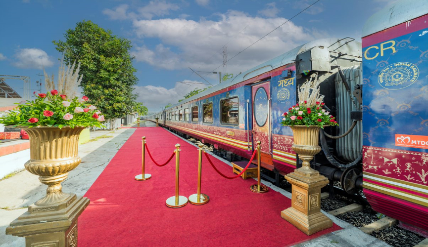The image shows a luxurious train at a station, with a red carpet and ornate floral arrangements on either side, creating an elegant and royal welcome for passengers.