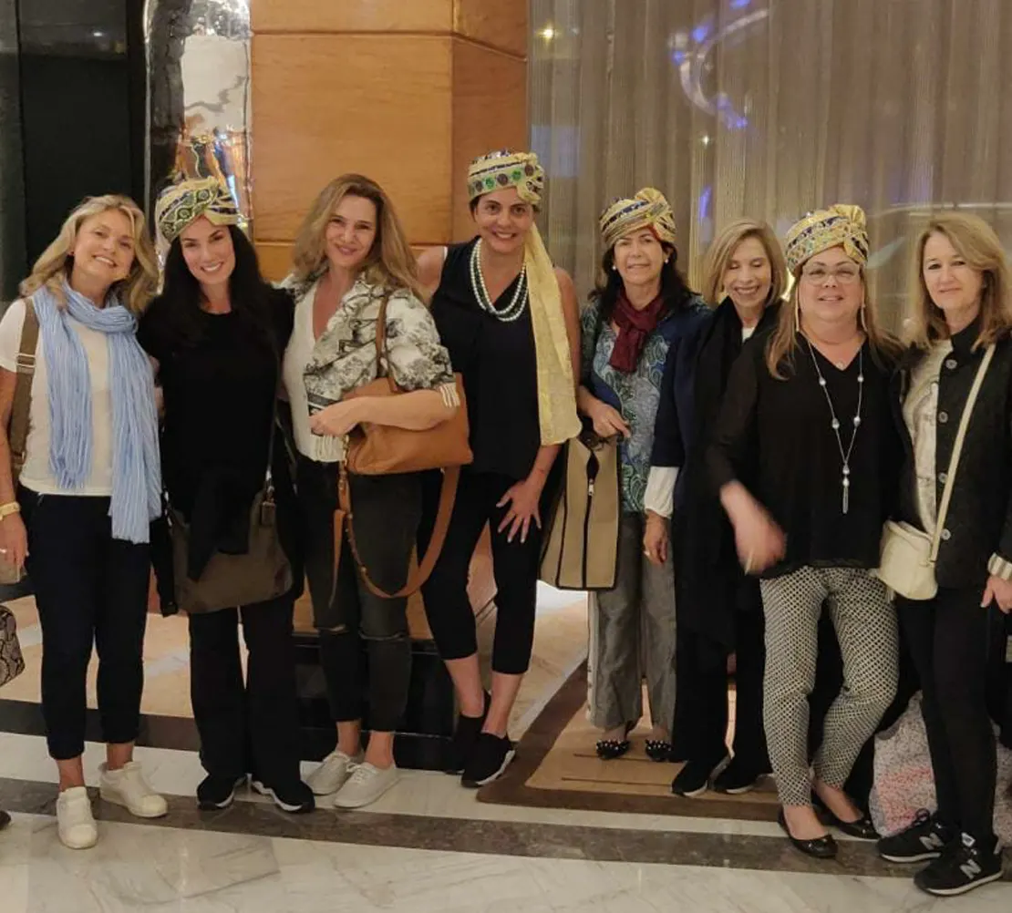 Group of women posing together indoors, several wearing traditional Indian turbans.