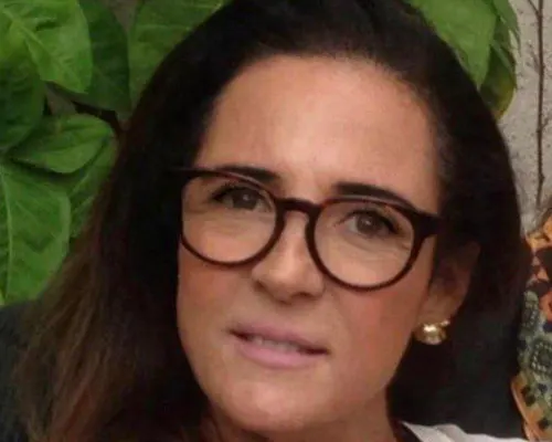 Close-up portrait of a woman with long dark hair wearing red cat-eye glasses.