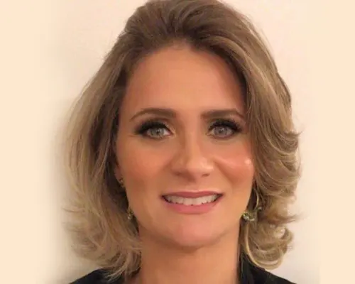 Headshot of a smiling woman with blonde hair and eye makeup.