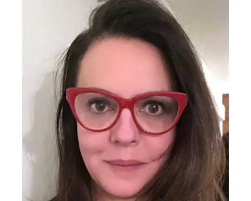 Close-up portrait of a woman with long dark hair wearing red cat-eye glasses.