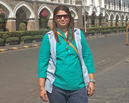 portrait of a woman with long dark hair wearing red cat-eye glasses.