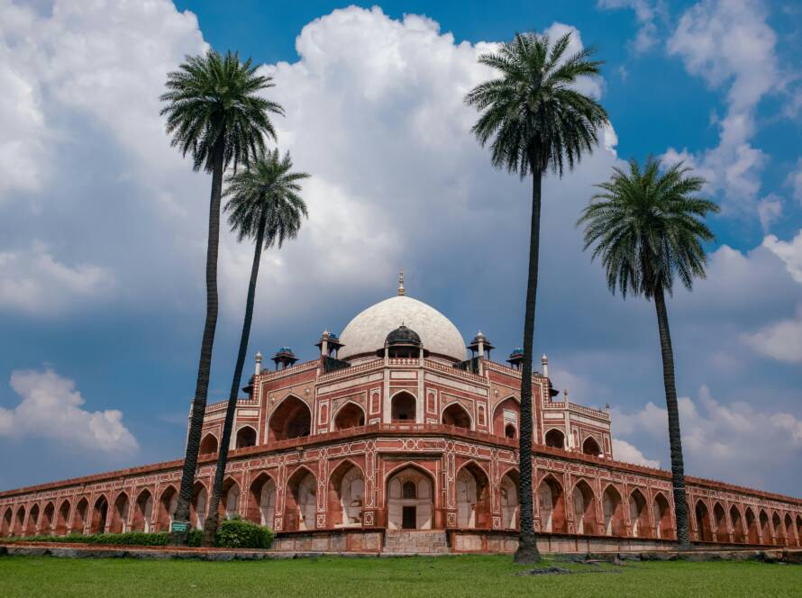 Majestic view of Humayun's Tomb in Delhi with lush greenery and palm trees, representing Iconic Monuments in India. 