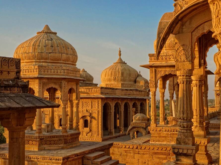 Jaisalmer golden sandstone architecture: Ornate domes, intricate carvings, decorated columns, traditional arches, and desert landscape cityscape