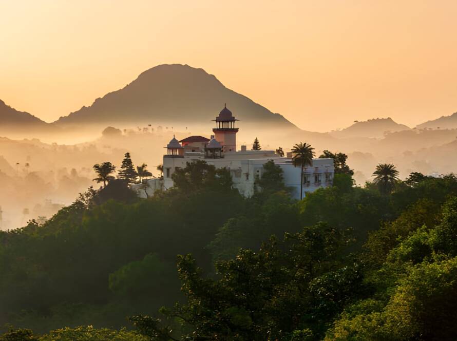 A majestic palace on a lush hilltop at sunrise in Mount Abu, showcasing tranquil scenery among the Best Hill Stations in India.