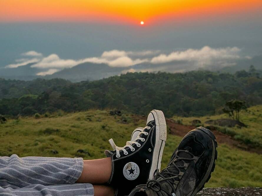 Sunrise over misty green hills in Munnar, viewed from a hiker’s perspective, highlighting its beauty as one of the Best Hill Stations in India.