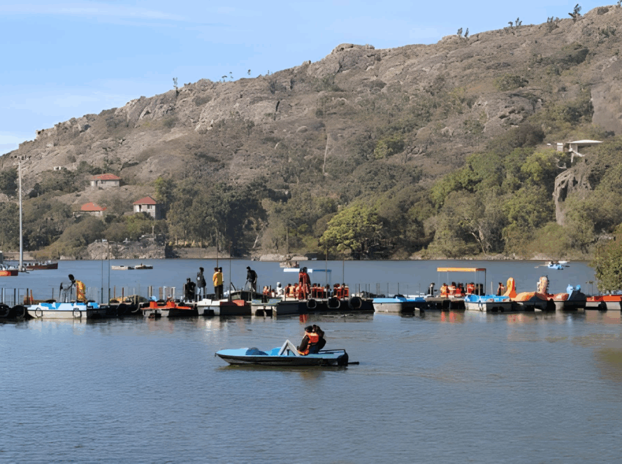 Nakki Lake in Mount Abu with people boating and surrounding hills, a popular scenic spot among tourist places to visit in Rajasthan.