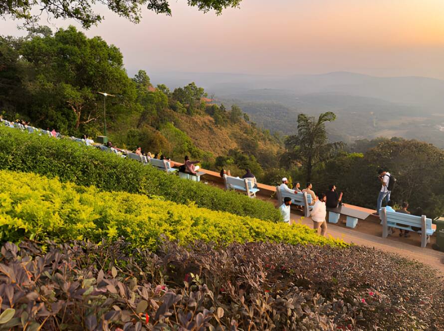 Tourists relaxing on benches at Raja’s Seat in Madikeri, enjoying sunset views over lush hills, exemplifying the Best Hill Stations in India.