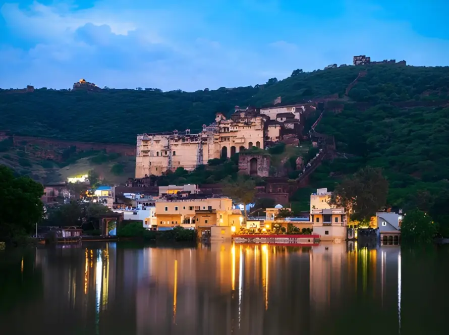 Nighttime view of Taragarh Fort and Garh Palace ruins in Bundi, Rajasthan, illuminated and reflected in the lake below, highlighting Underrated Places in India.