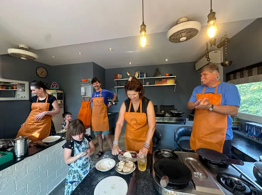 Guests enjoying a curated cooking class with renowned chefs during a Bespoke Luxury India Tour, learning traditional culinary skills