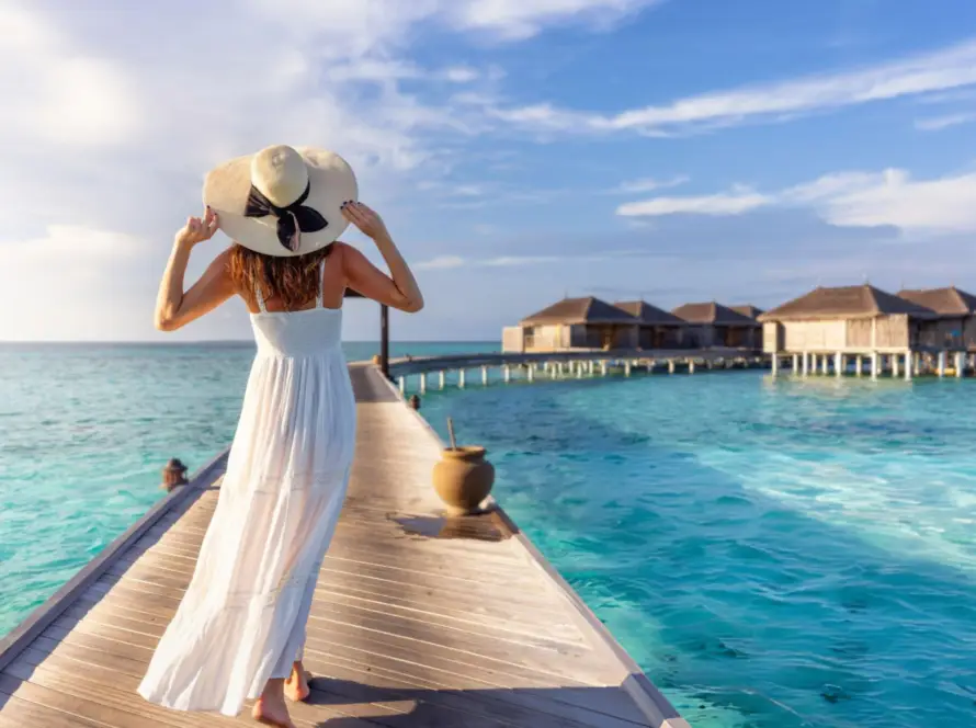 A traveler walking along a pier towards overwater bungalows in the Maldives, a luxurious South Asian Gem surrounded by crystal-clear waters.