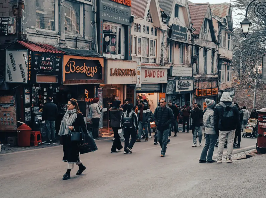 A bustling street view of The Mall Road in Shimla, featuring various shops and people walking, suitable for Honeymoon Destinations in India.