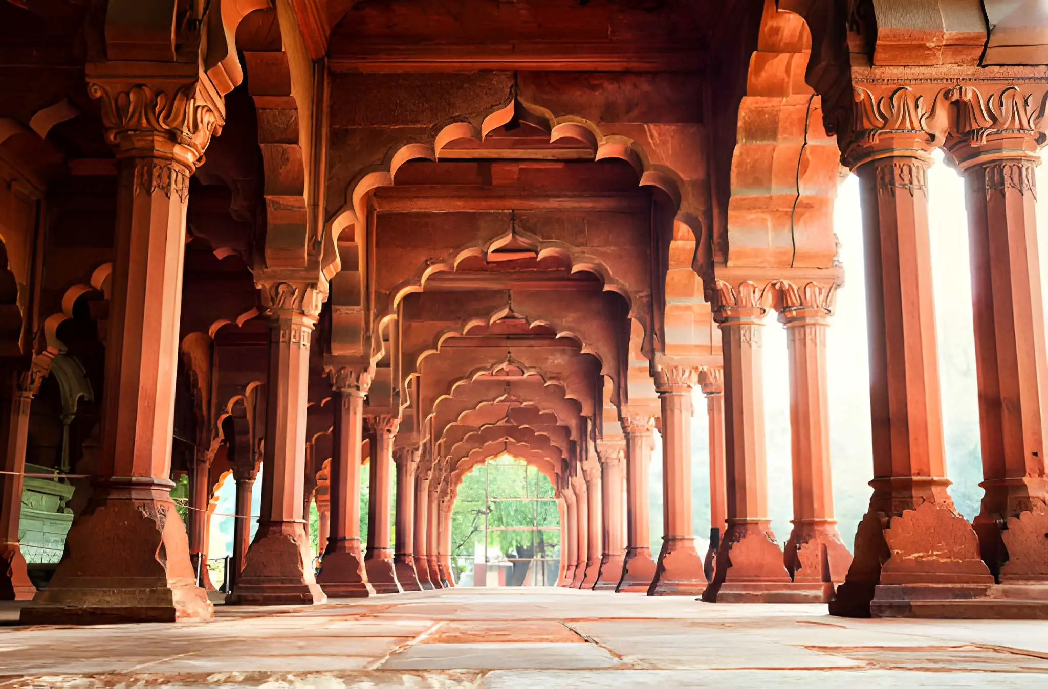 Red Fort Delhi interior corridor with red sandstone pillars, ornate capitals, arches, and symmetrical architectural design 